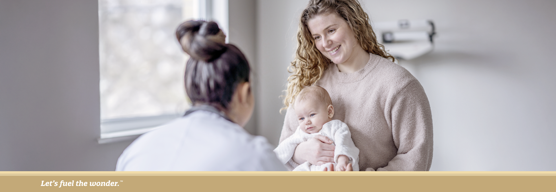 Mother holding baby while talking to a pediatrician during a medical visit.