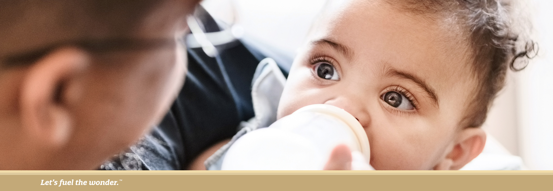 Father feeding baby with a bottle while holding them in his arms.