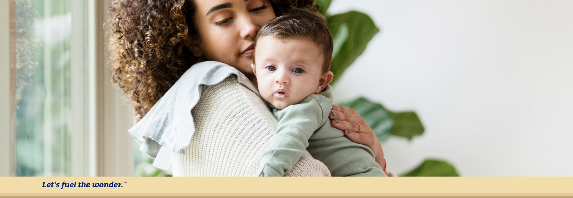 Baby with mild puke around lips being held by sitting mother in  mother's right arm. Baby is leaned over mother's right shoulder  while mother rests their left hand on baby's back