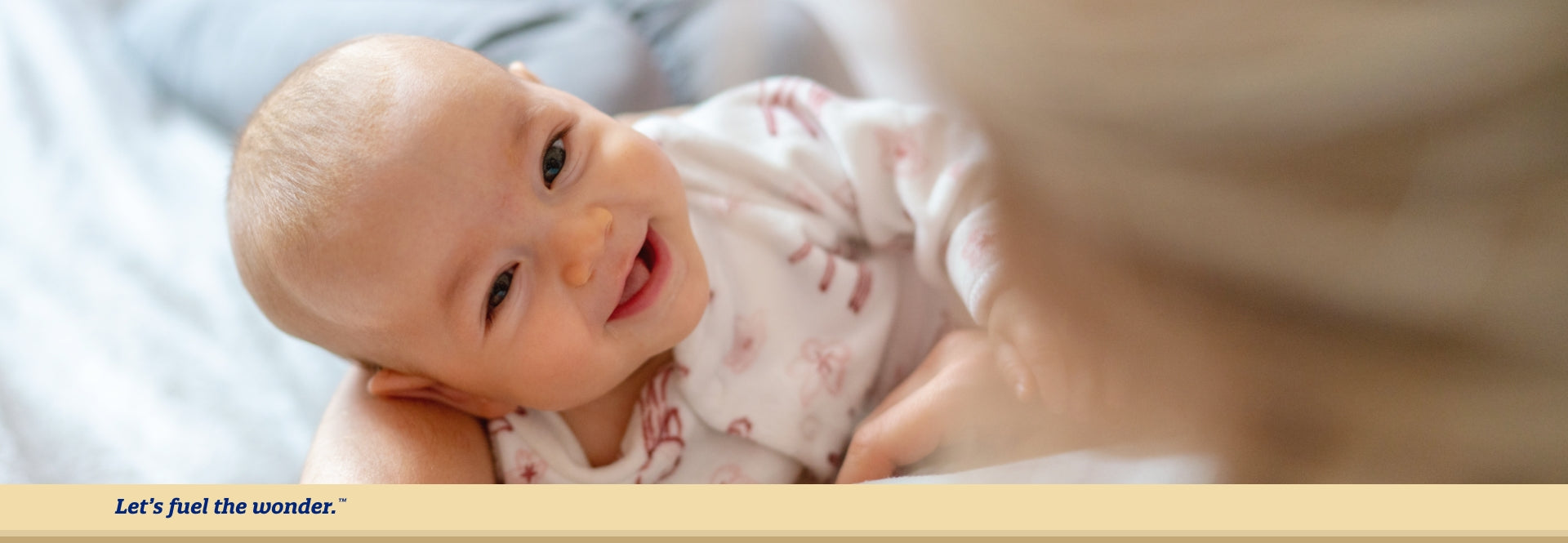 Smiling baby resting on their side while looking at parent who is holding baby's head up