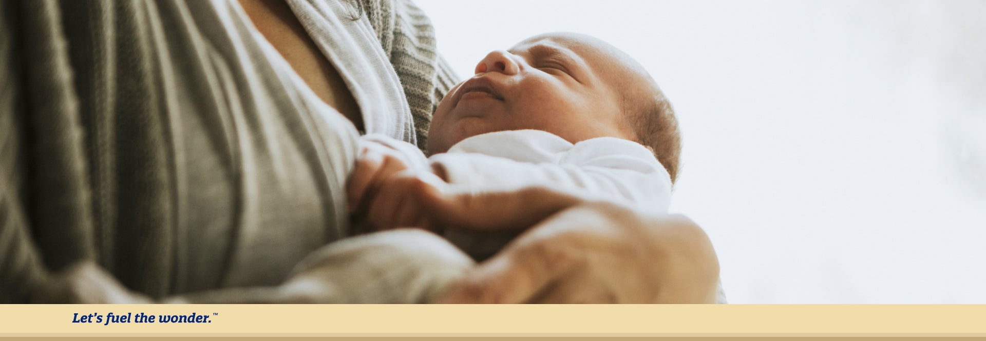 Sleeping baby being held closely to mother's chest in mother's left arm