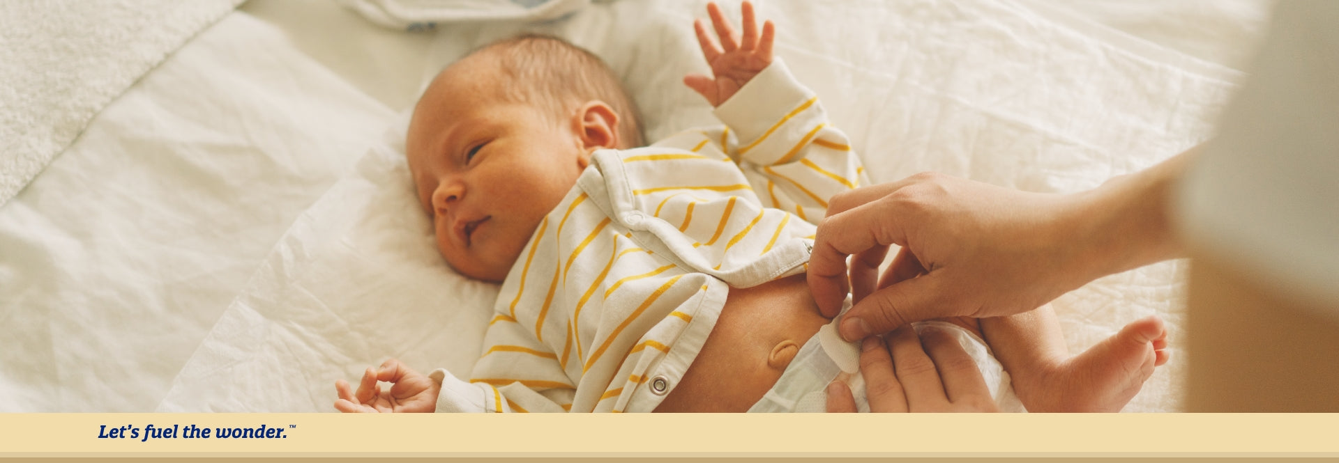 Baby with eyes nearly closed and hands out laying on bed while parent changes baby's diaper