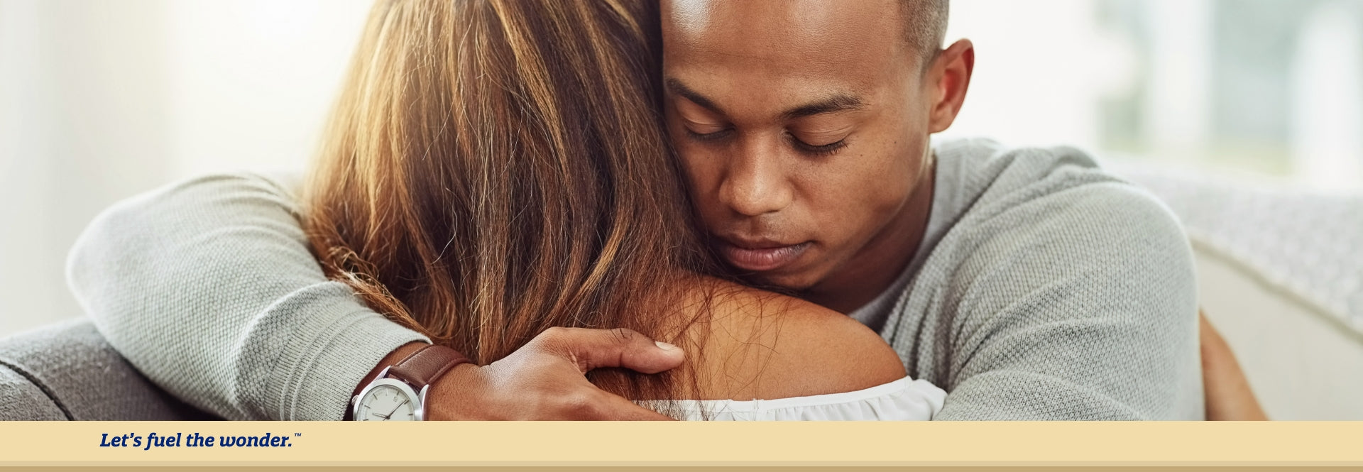 Parent with eyes closed hugging other parent over the shoulder while sitting down