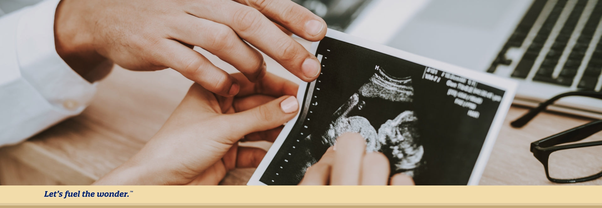 Parent sitting down holding ultrasound results while doctor points subtly points to the same screenshot