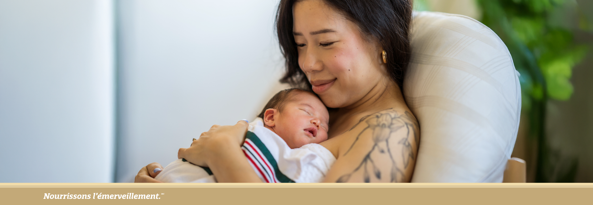 Mother cuddling her sleeping newborn, smiling gently while 
seated on a couch. - FR