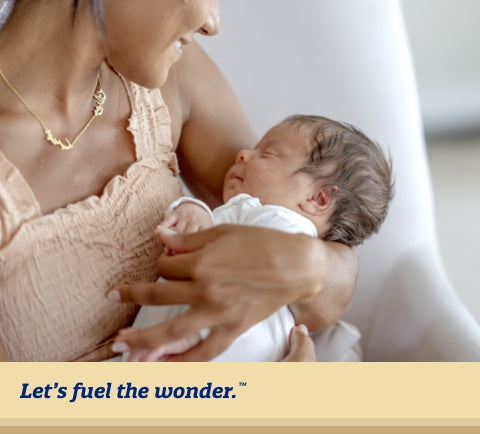 Sleeping baby being held in arms of smiling parent